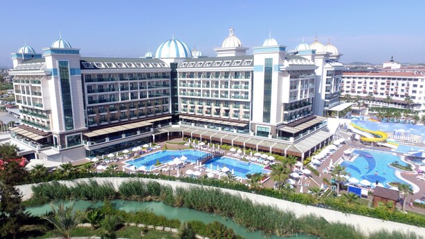 A large hotel with multiple floors, a central courtyard with a pool, and a view of the surrounding landscape.