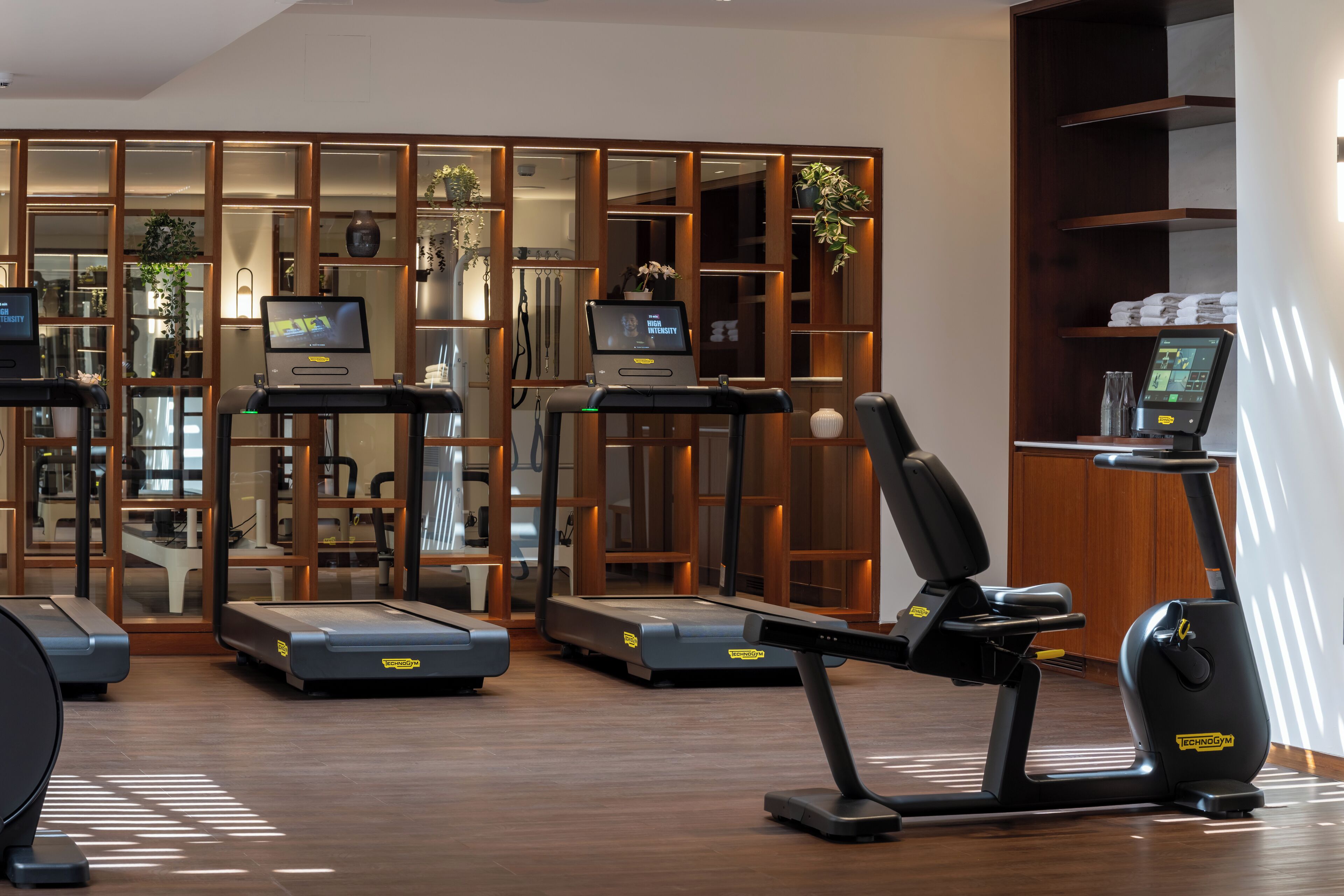 Un gimnasio con cintas de correr, una bicicleta estática y una máquina de remo.