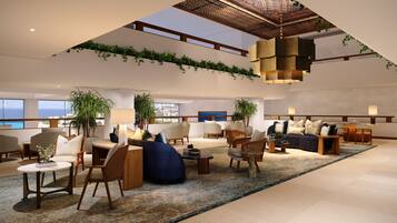 A spacious living area with multiple seating options, a large window offering a view of the sea, and a ceiling with a unique design.