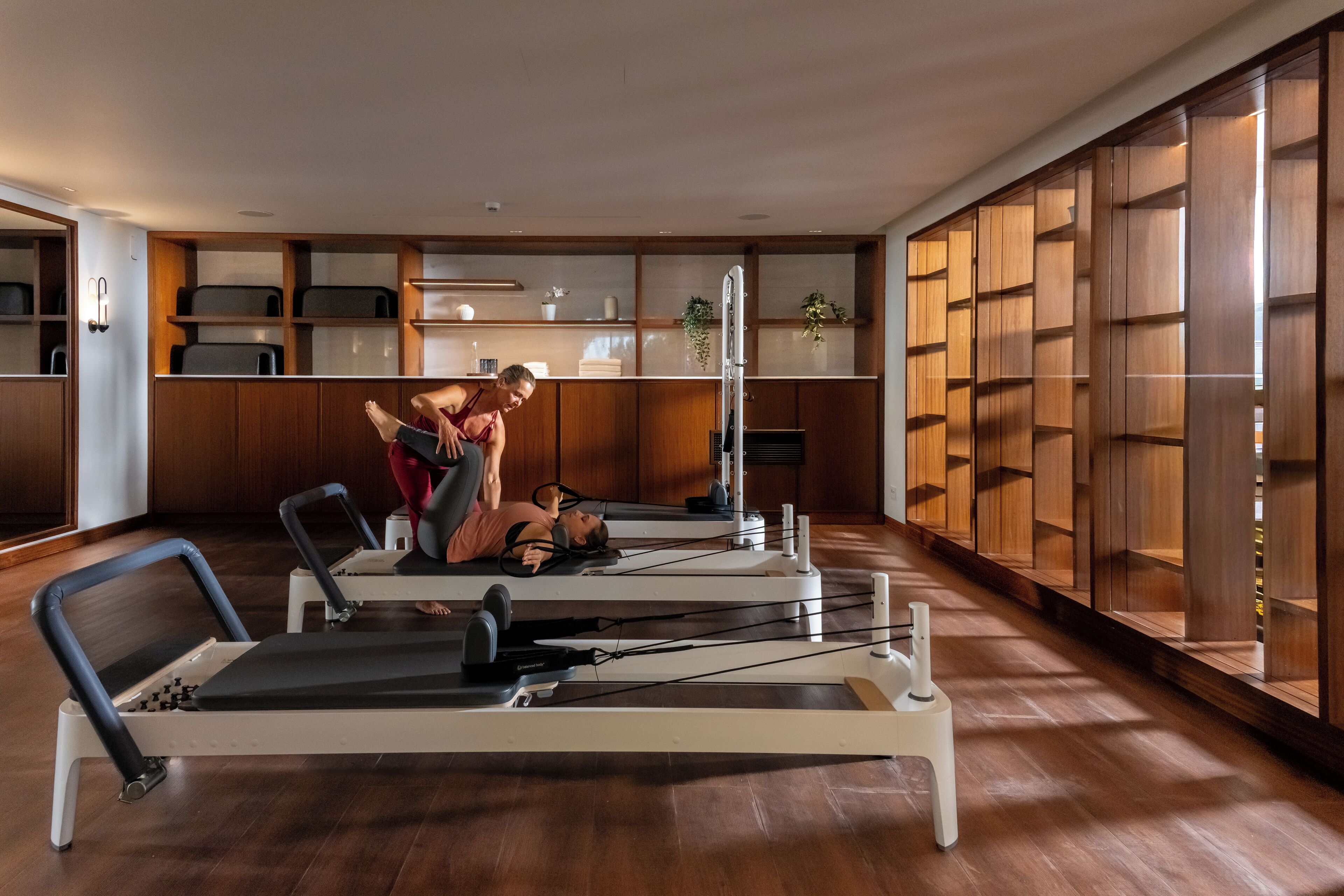 A Pilates studio with two exercise machines, wooden cabinets, and a large window.
