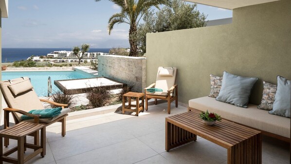 A terrace with a pool, lounge chairs, a sofa, and a table. - Porto Elounda Golf & Spa Resort (Agios Nikolaos)