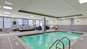 An indoor swimming pool with clear lane markings, lounge chairs, and a lifeguard station. - Hampton Inn & Suites by Hilton Saskatoon Airport (Saskatoon)