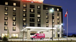 A Hampton Inn & Suites hotel with a red van parked in front. - Hampton Inn & Suites by Hilton Saskatoon Airport (Saskatoon)
