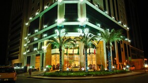 A multi-story hotel with balconies, palm trees, and a well-lit entrance. - Best Western Plus Doha (Doha)