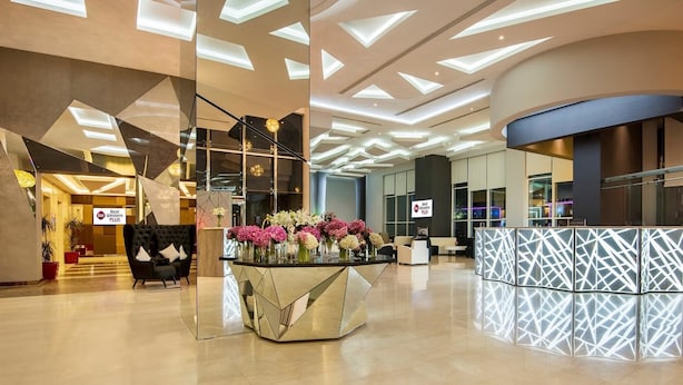 A modern hotel lobby with a central reception desk, seating area, and a staircase leading to upper floors. - Best Western Plus Doha (Doha)
