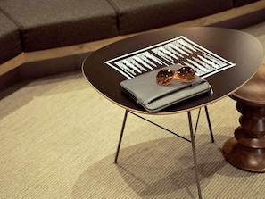Une table ronde avec un plateau noir et des pieds dorés, un carnet gris et une paire de lunettes de soleil posées dessus.