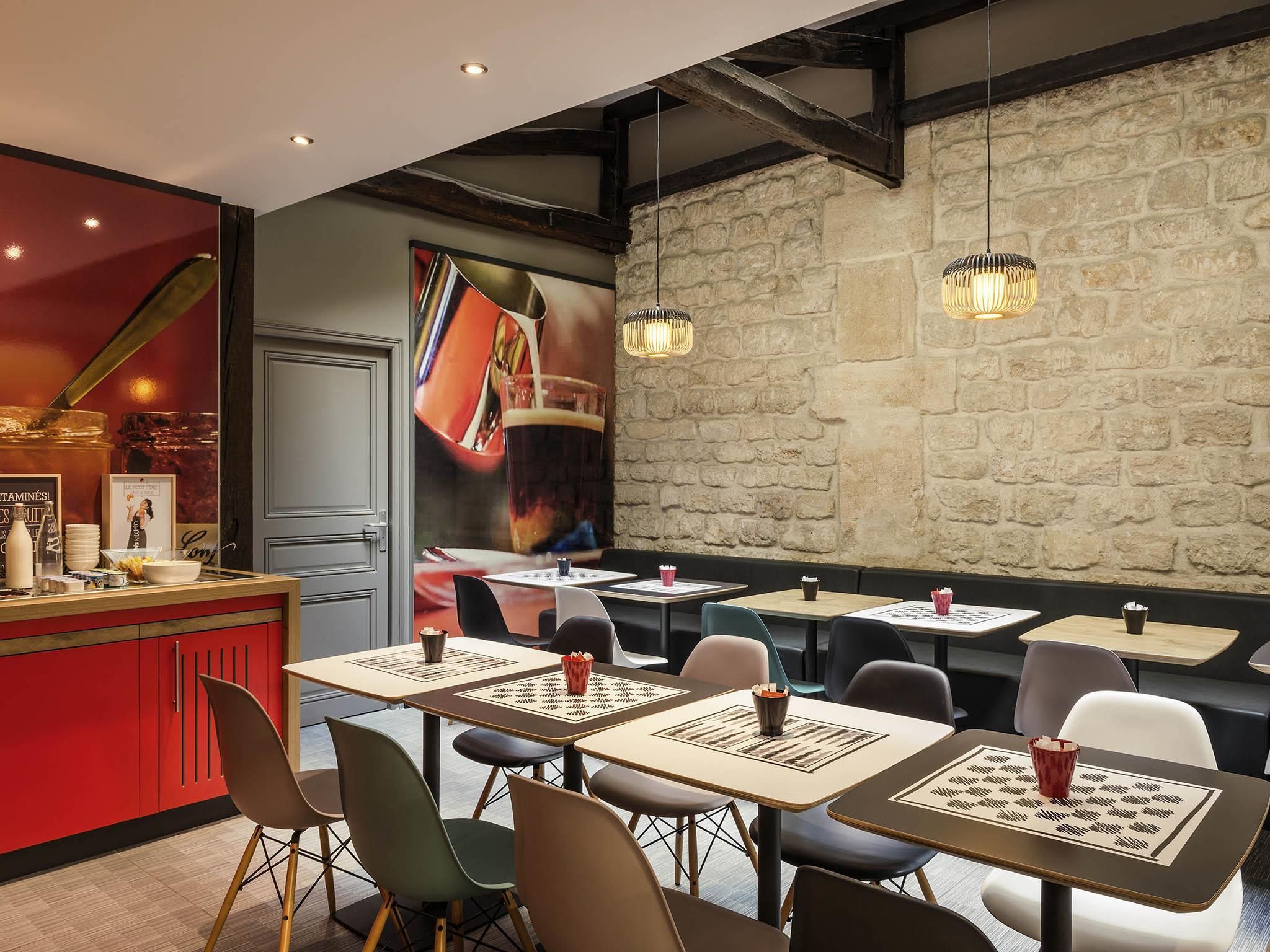 A restaurant interior with tables, chairs, a bar area, and a stone wall.