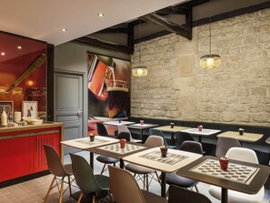 Ein Restaurantinneres mit Tischen, Stühlen, einer Bar und einer Steinwand.