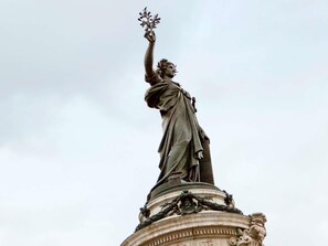 A statue of a figure holding a branch with leaves, standing on a pedestal with ornate carvings. - Ibis Paris Avenue De La Republique (Paris)