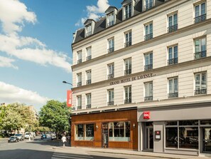 Een meerlaags hotel met een klassiek gevelontwerp, grote ramen en een opvallend bord met de tekst 'Grand Hotel de L'avenue'.