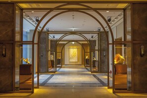 A hotel lobby with a marble floor, glass display cases with sculptures, and a central art piece on the wall. - Taipei Marriott Hotel (Taipei)