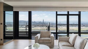 A modern living room with a large window, a sofa, a chair, and a glass coffee table. - Taipei Marriott Hotel (Taipei)