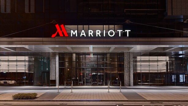 A Marriott hotel entrance with a modern glass facade, large windows, and a prominent red logo. - Taipei Marriott Hotel (Taipei)