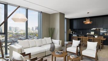 A modern living room with a large sofa, wooden chairs, and a dining area.