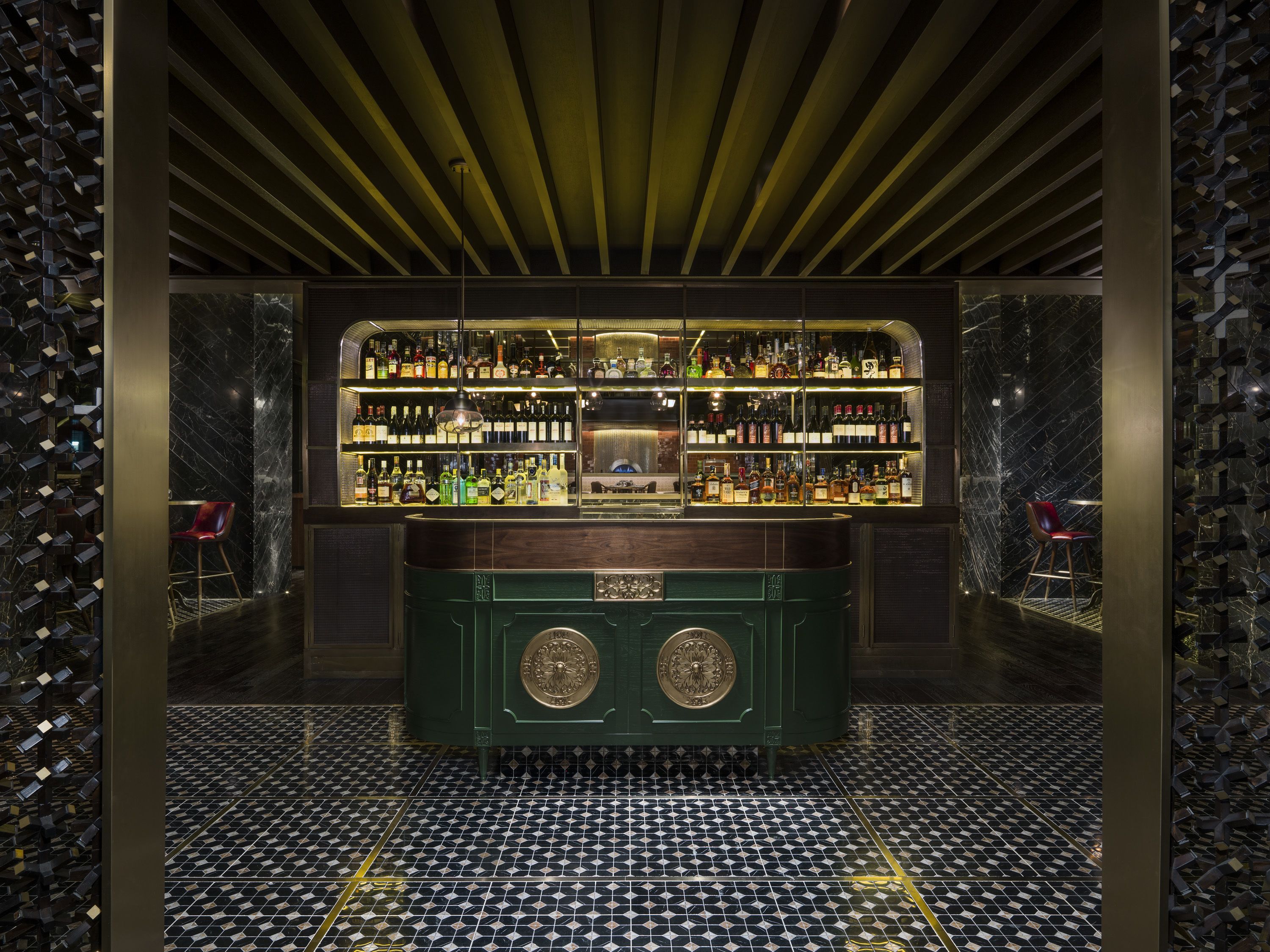 A bar area with a green counter, shelves of liquor bottles, and a patterned floor.