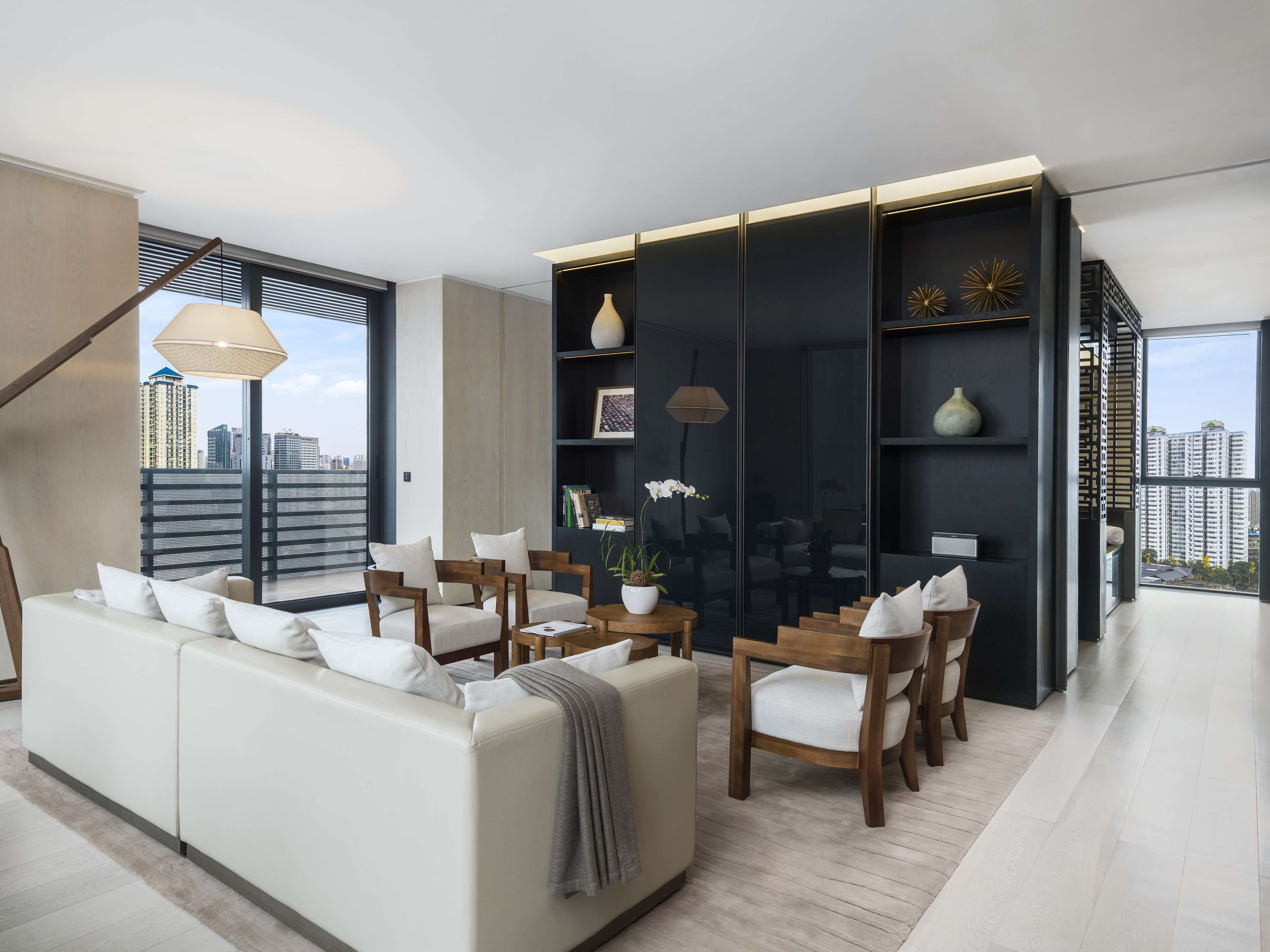 Una sala de estar moderna con sofá, sillones, una mesa de centro y una estantería.