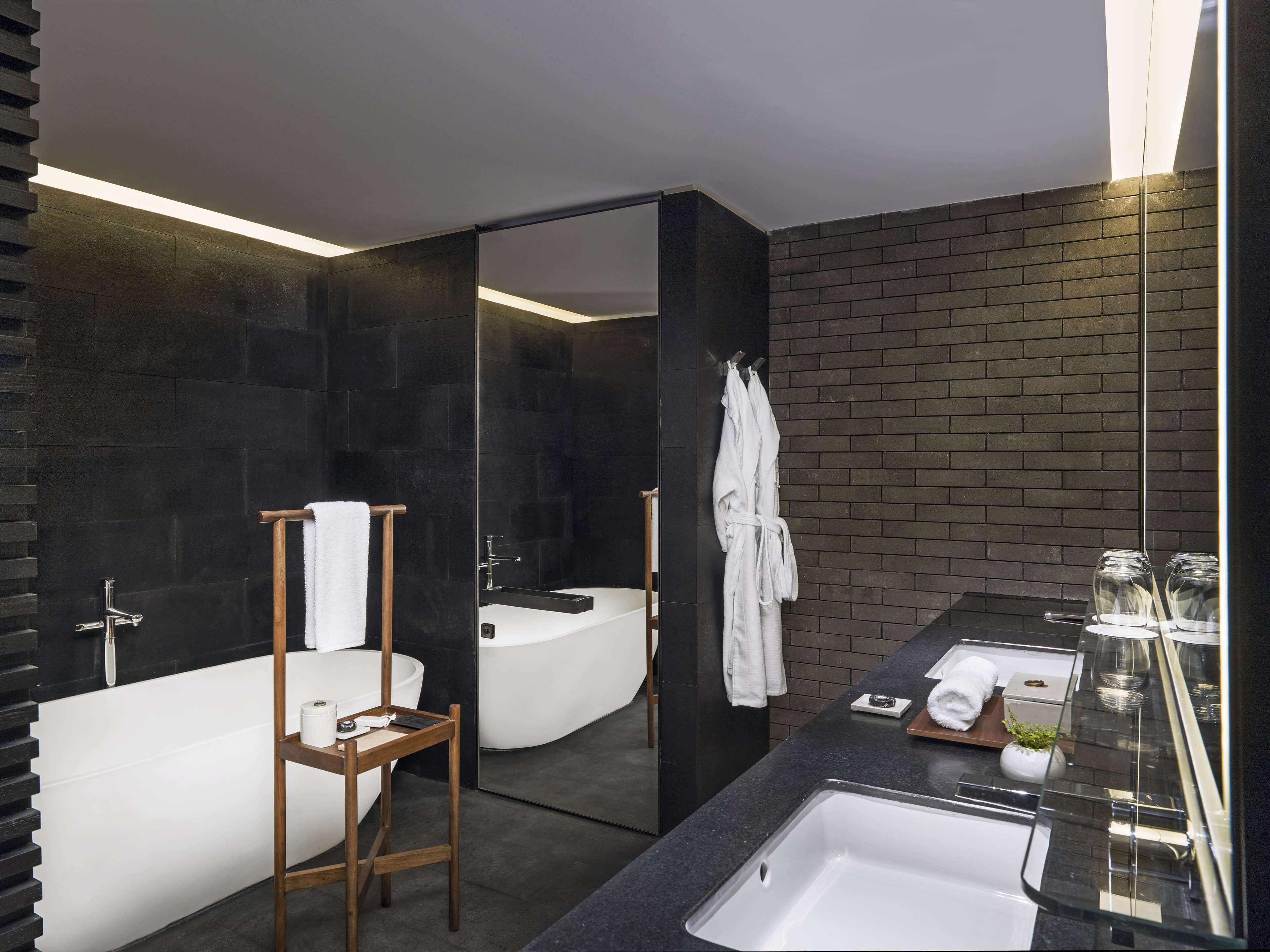 A modern bathroom with a bathtub, a large mirror, and a vanity with a sink.