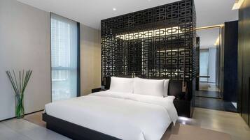 Una habitación de hotel moderna con una cama grande, un panel decorativo negro y vistas de la ciudad.