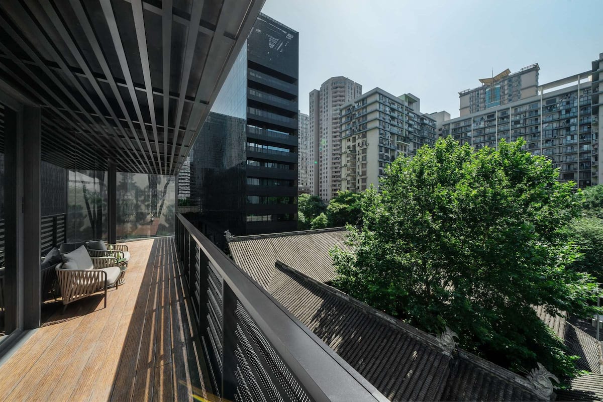 A modern building with a balcony, wooden flooring, and a view of surrounding high-rise buildings.