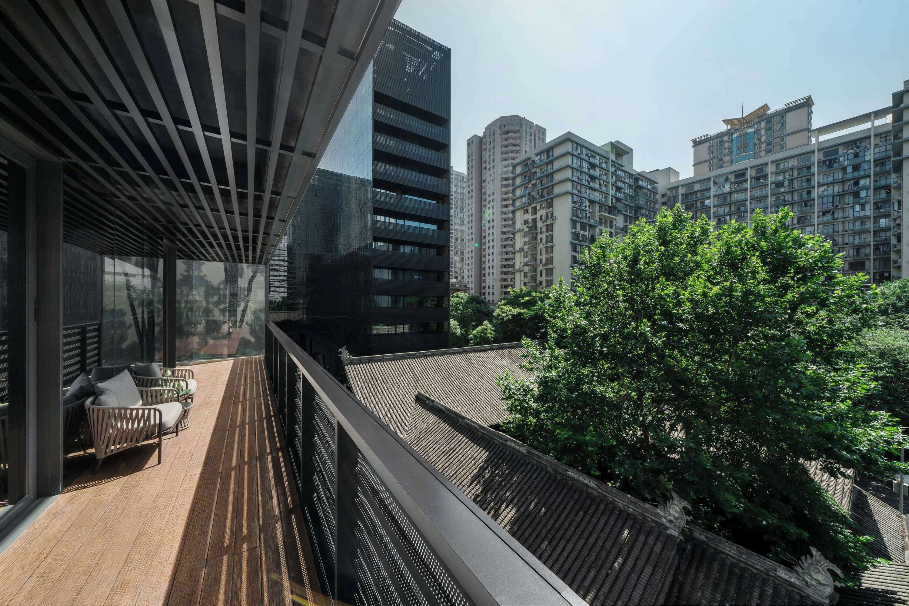 A modern building with a balcony, large windows, and a view of surrounding high-rise buildings.