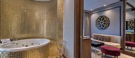 A modern bathroom with a freestanding bathtub, a vanity with a mirror, and a seating area with a sofa and ottoman.
