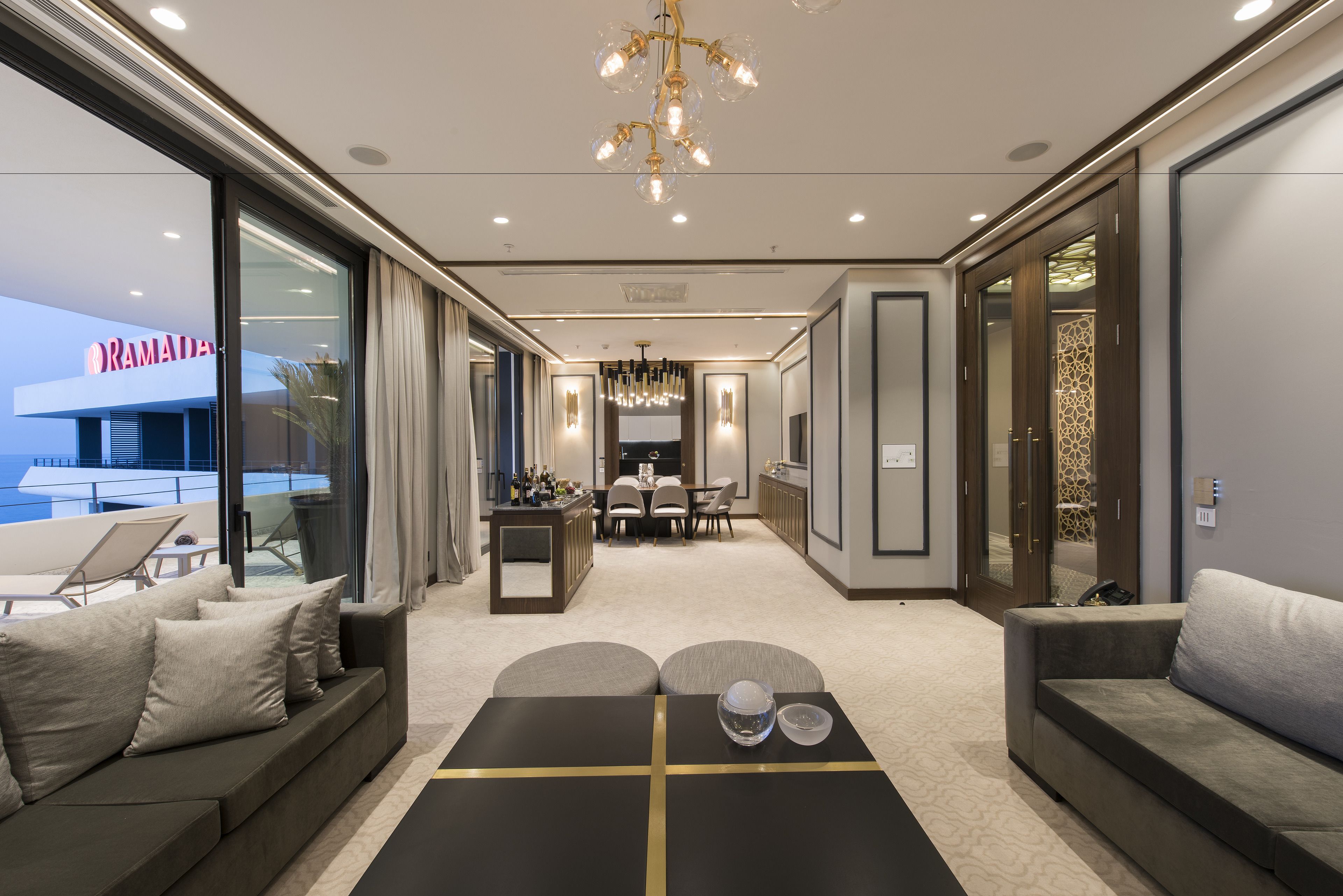 A modern hotel lobby with a dining area, sofas, and a view of the outside.