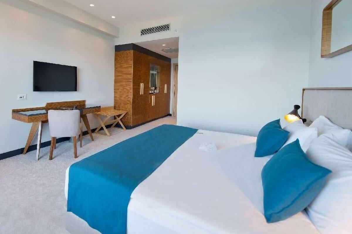 Une chambre d’hôtel comprenant un lit, un bureau, une chaise, une télévision et une armoire.