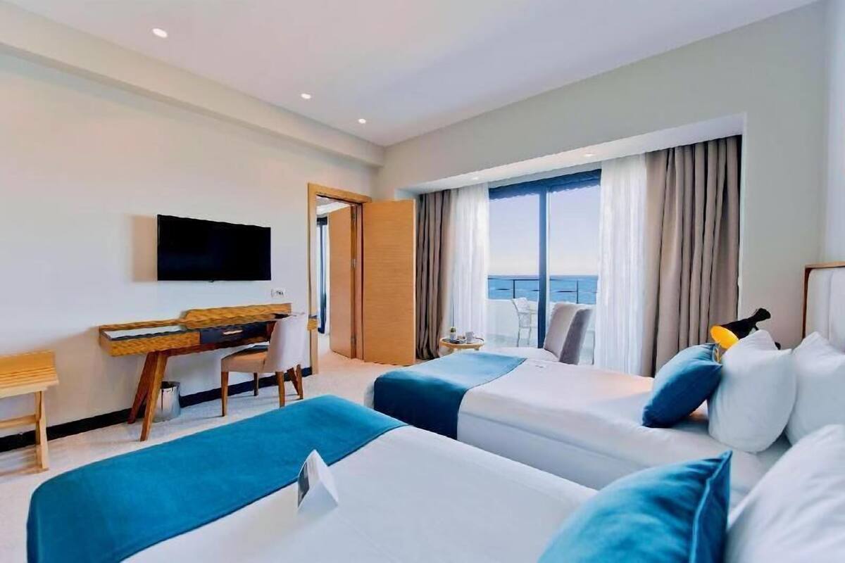 Une chambre d’hôtel avec deux lits, un bureau, une télévision et un balcon avec vue.
