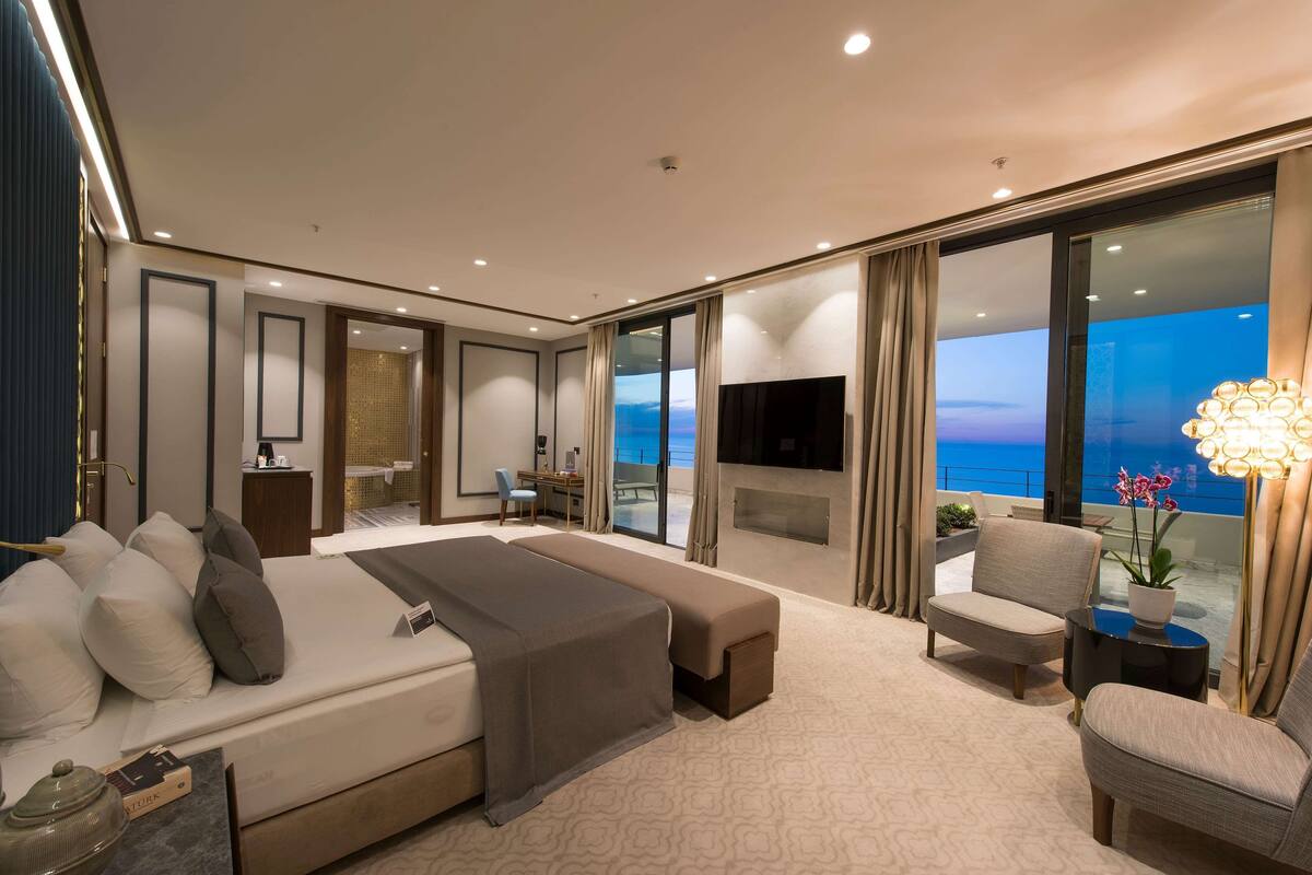 Une chambre d’hôtel moderne dotée d’un grand lit, d’un coin salon avec vue et d’un balcon avec télévision.