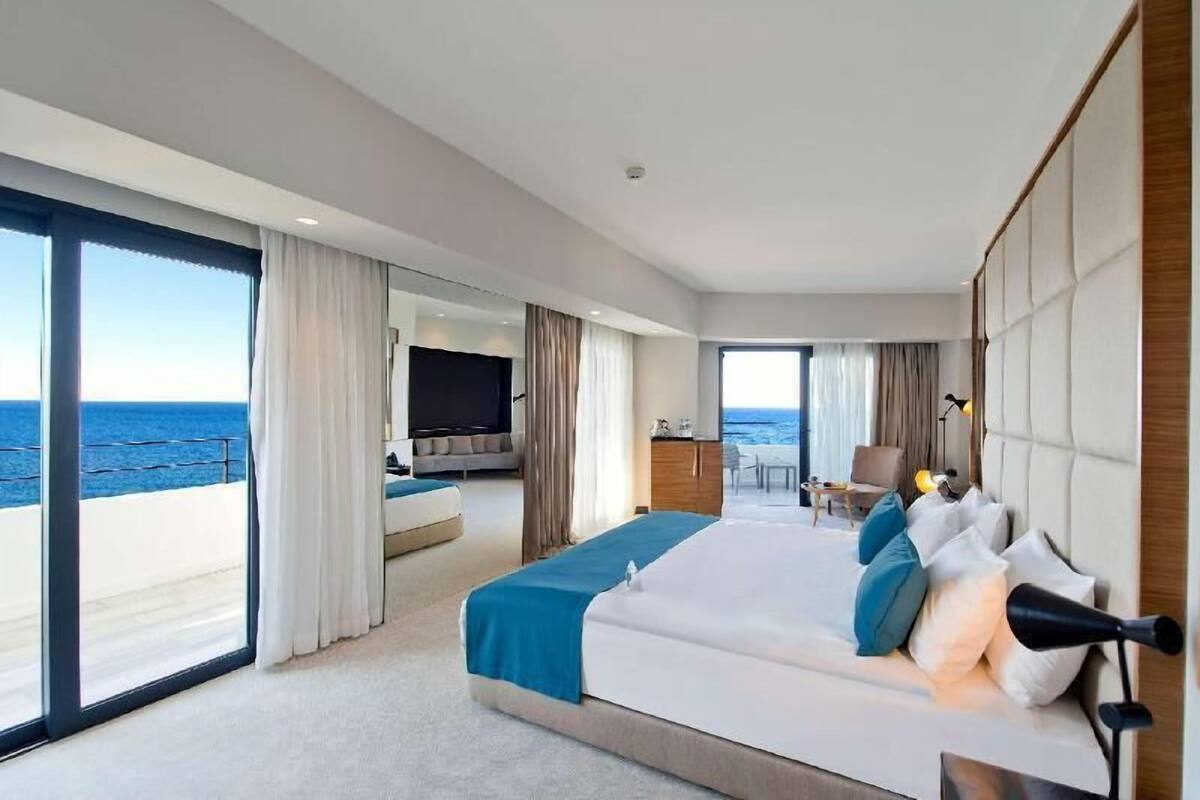 Une chambre d’hôtel avec un grand lit, un bureau, une chaise et une vue sur l’océan.