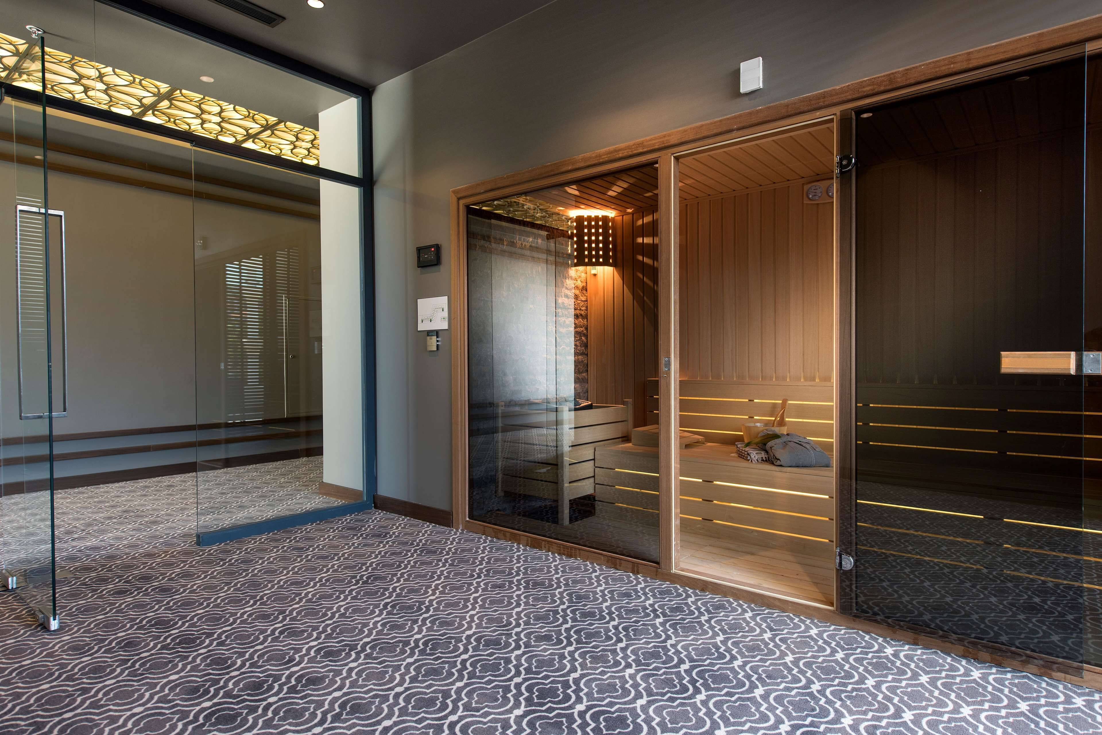 A modern interior with a patterned floor, a glass partition, and a wooden sliding door leading to a sauna area.