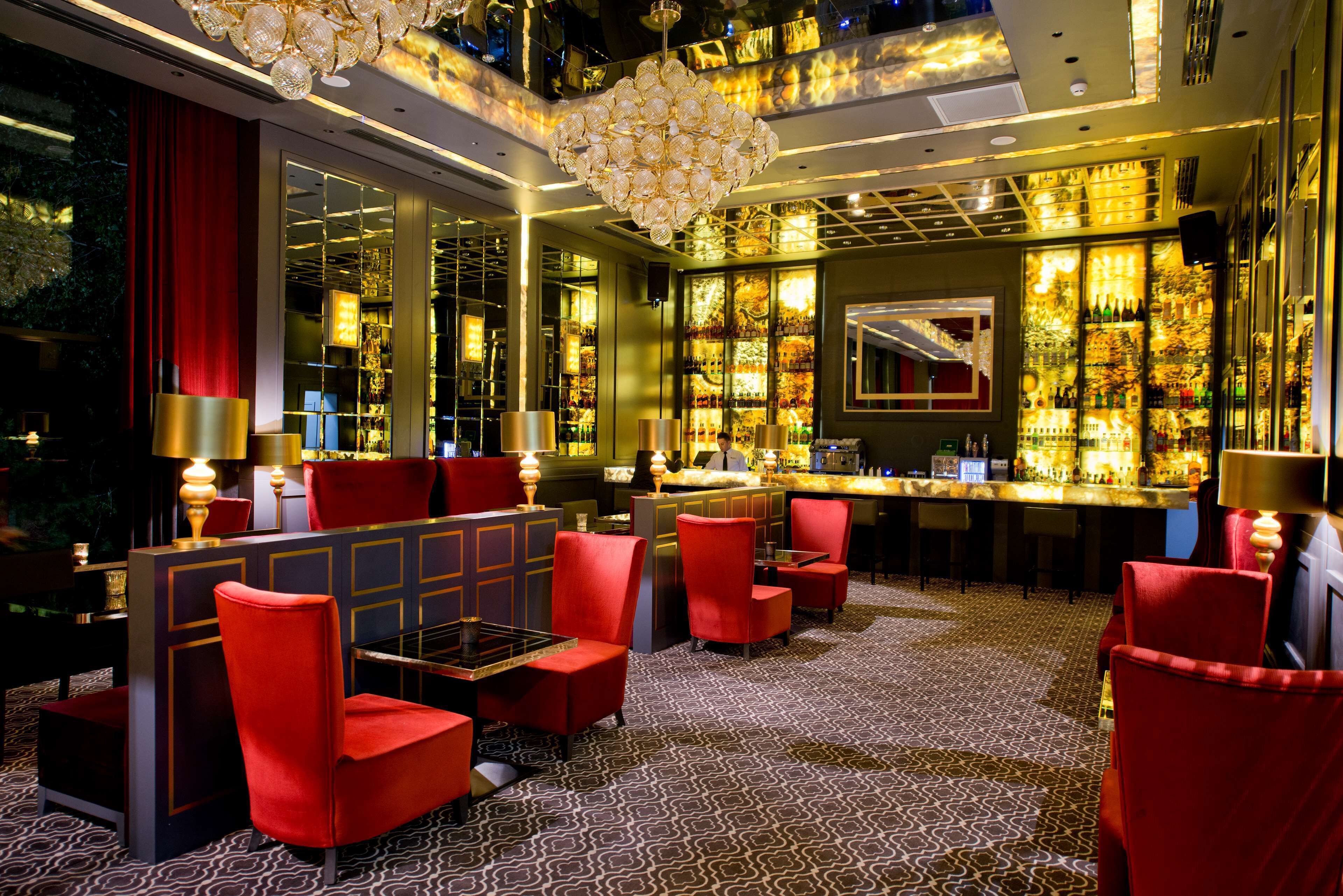 Eine Bar mit roten Stühlen, einer Theke und einer Kristallleuchtre.