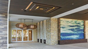 A modern lobby with a mosaic wall, wooden ceiling, and a large entrance door. - Warwick Paradise Island- All Inclusive- Adults Only (Paradise Island)