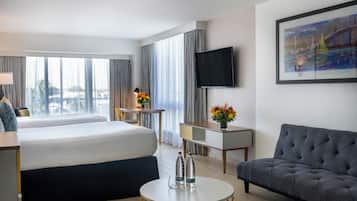 Una habitación de hotel con cama, escritorio, sofá, televisión y un cuadro en la pared.
