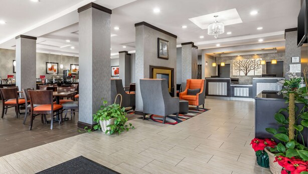 A hotel lobby with seating areas, a reception desk, and a dining area.