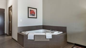 A modern bathroom with a freestanding bathtub, a framed picture on the wall, and a striped rug on the floor.