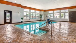 A large indoor swimming pool with clear blue water, surrounded by a tiled floor and wooden accents.