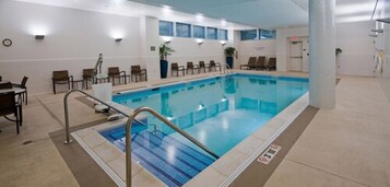Una piscina interior con línea de agua transparente, rodeada de sillones de descanso y una zona de solárium.