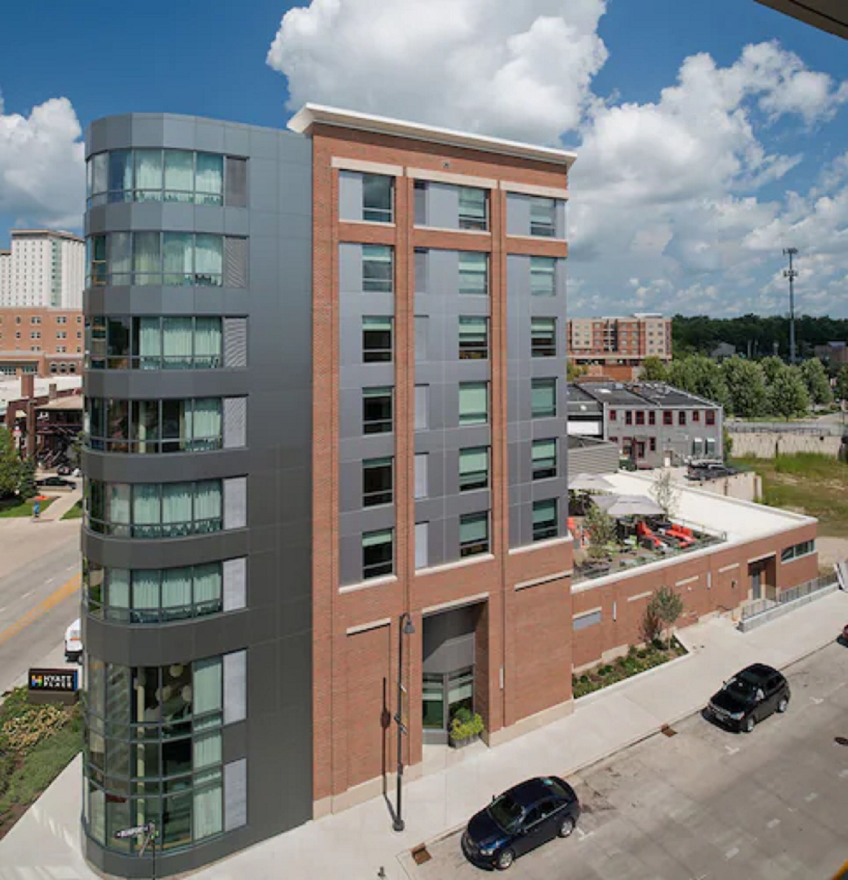 A multi-story building with a mix of glass and brick facade, featuring a central entrance and multiple windows.