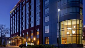 Un hotel de varios pisos con diseño moderno, que destaca por una entrada imponente con zona cubierta y una amplia fachada de vidrio en un lateral.