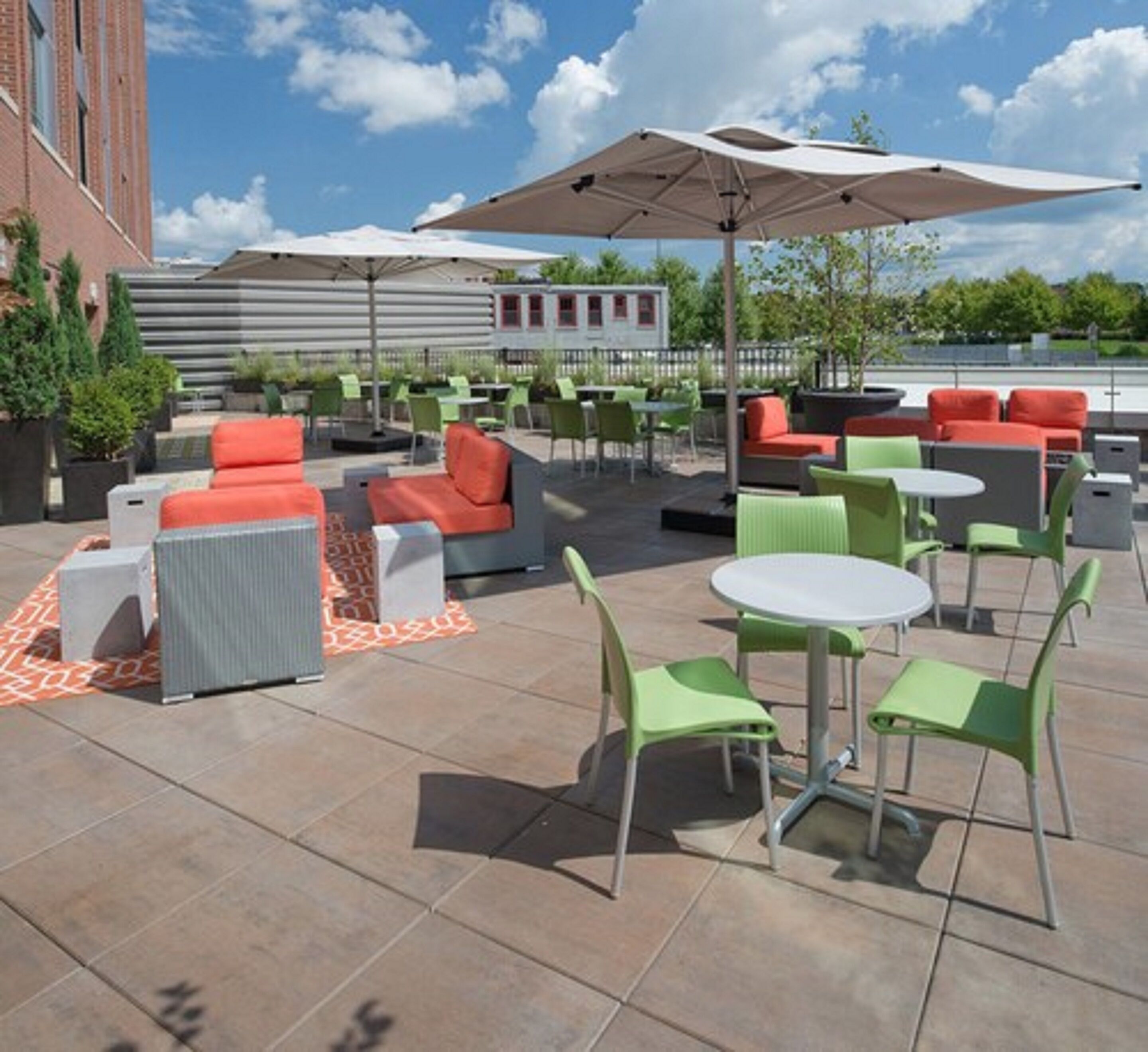 An outdoor patio area with seating arrangements, including sofas and chairs, under large umbrellas.