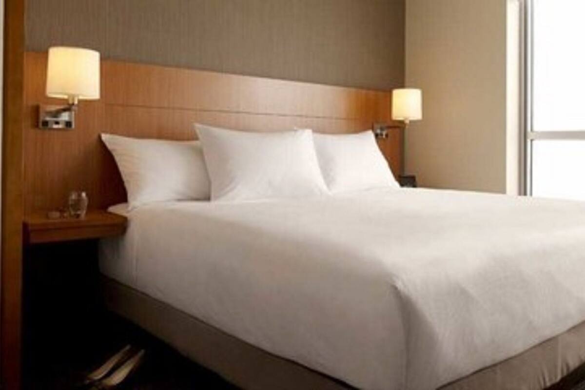 A hotel room with a large bed, two bedside tables, and a window.