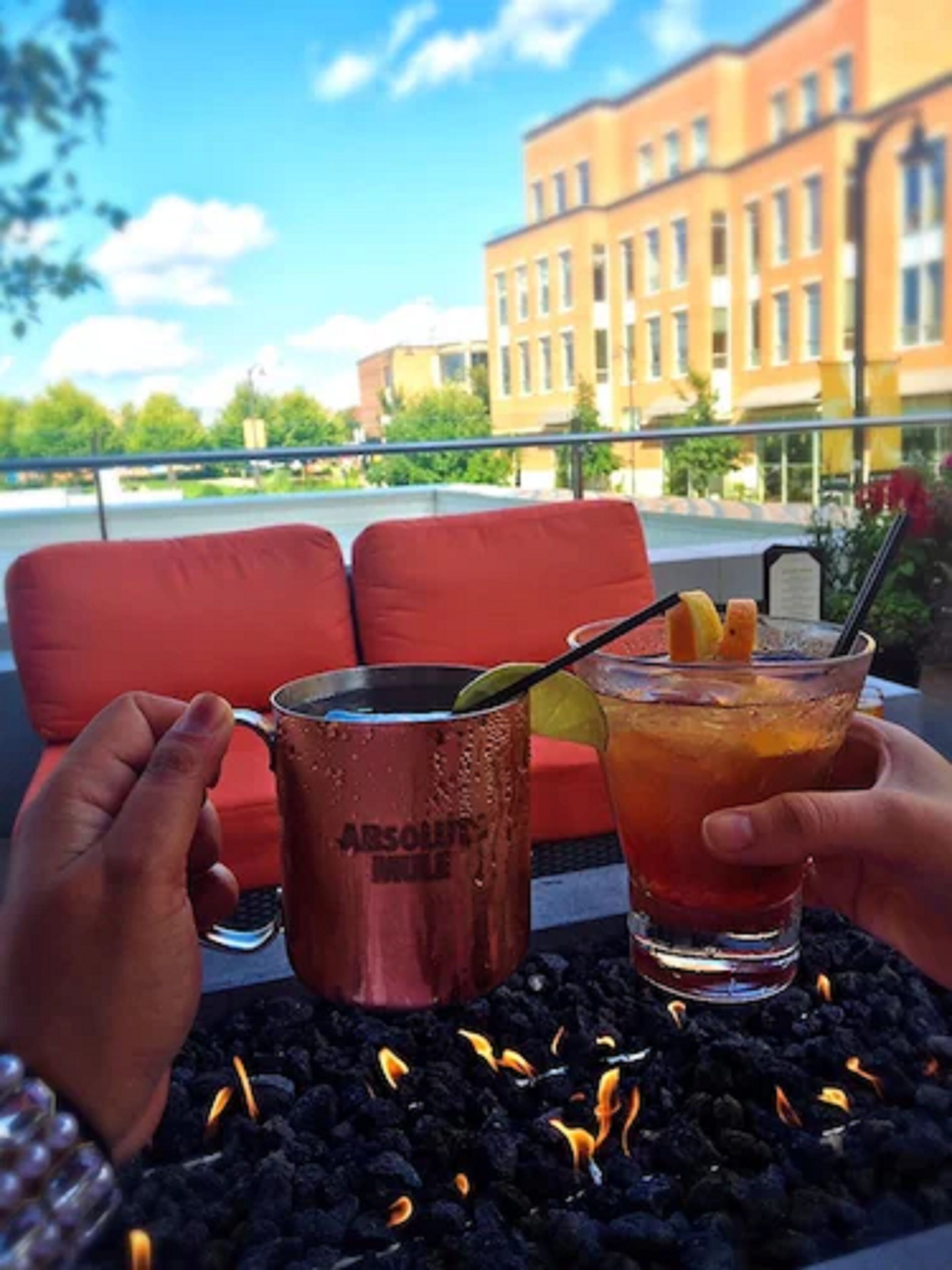 Two drinks on a table with a cityscape view.