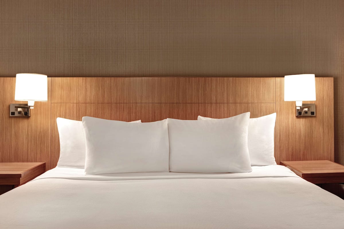 A hotel room with a large bed, two bedside tables, and wall-mounted lamps.