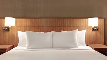 A hotel room with a large bed, two bedside tables, and wall-mounted lamps.