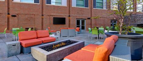 An outdoor seating area with orange sofas, green chairs, and a fire pit.