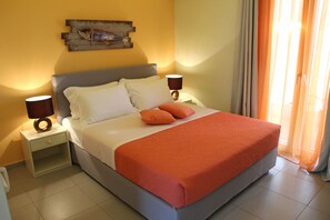 Una cama bien hecha con un edredón naranja, dos lámparas de noche y una obra de arte colgada en la pared.