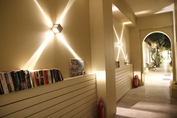 A hallway with bookshelves, a fire extinguisher, and a painting on the wall.