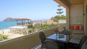 A balcony with a dining table, chairs, and a view of the sea. - Effi Apartments (Platanias)