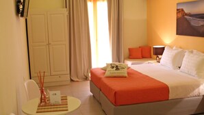 A hotel room with a bed, a desk with a chair, a table, and a wardrobe. - Effi Apartments (Platanias)